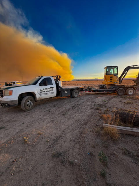 ClearPath truck hauling an excavator for dirt work and excavation in Pueblo County at sunset